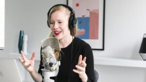 girl with headphones recording with a microphone in front of a computer