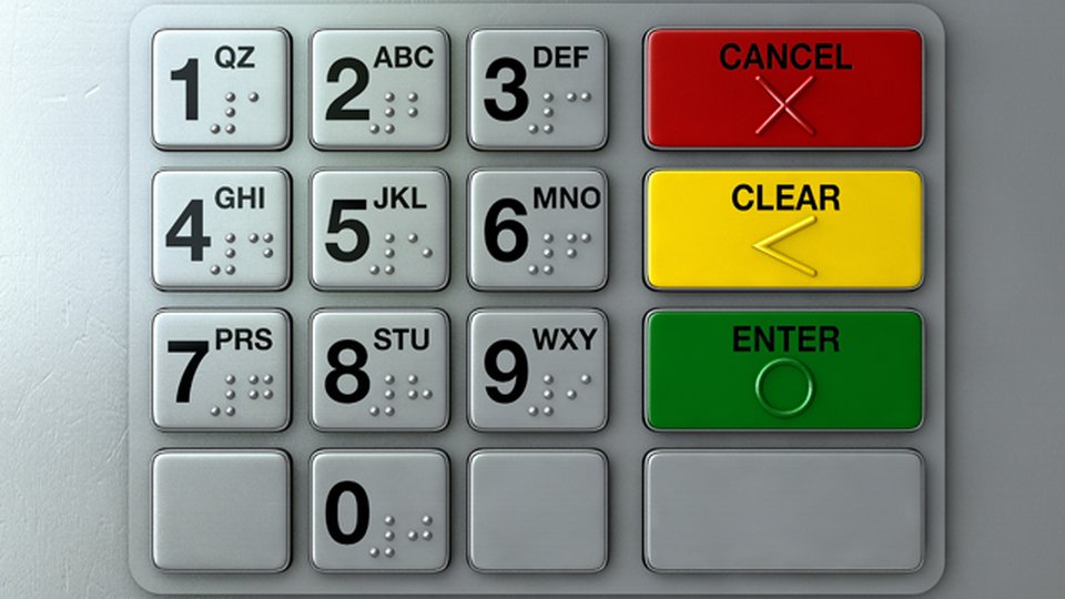 Close-up of a metallic ATM number pad featuring raised Braille dots on each key, with prominent colored 'Cancel' (red), 'Clear' (yellow), and 'Enter' (green) buttons for tactile accessibility.